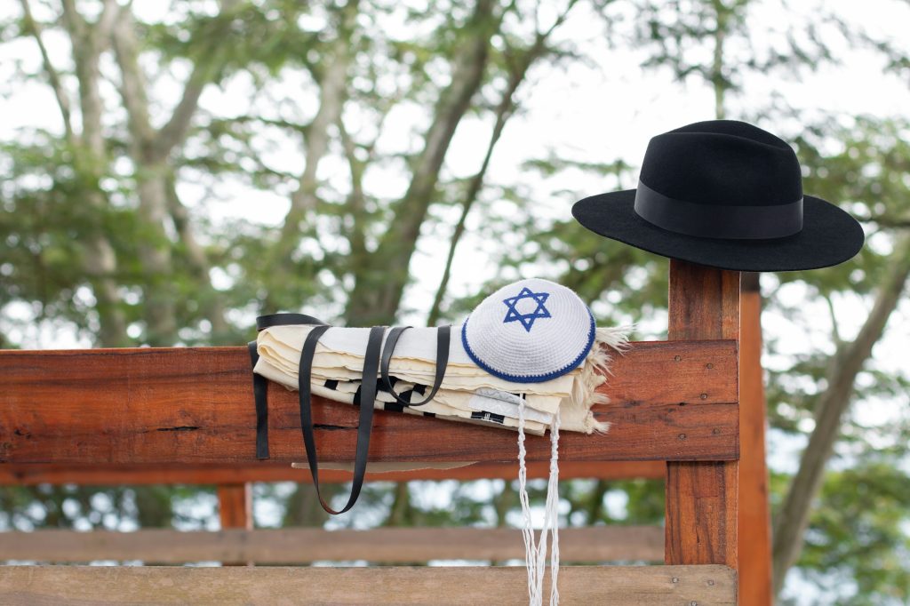 Jewish religious objects together on a wood. kipa, tallit, Tzitzit, tefillin, hat.